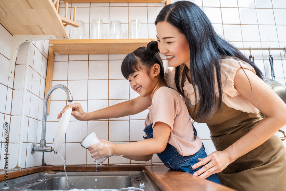 亚洲母亲教孩子女儿在家里的厨房洗碗