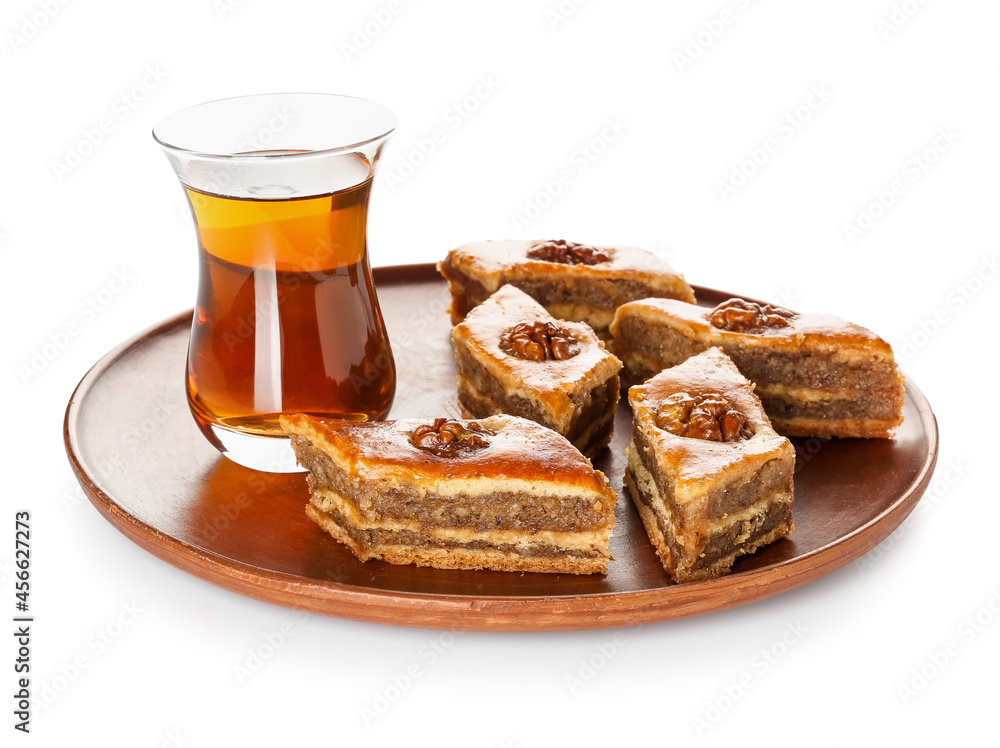Plate with tasty baklava and glass of Turkish tea on white background