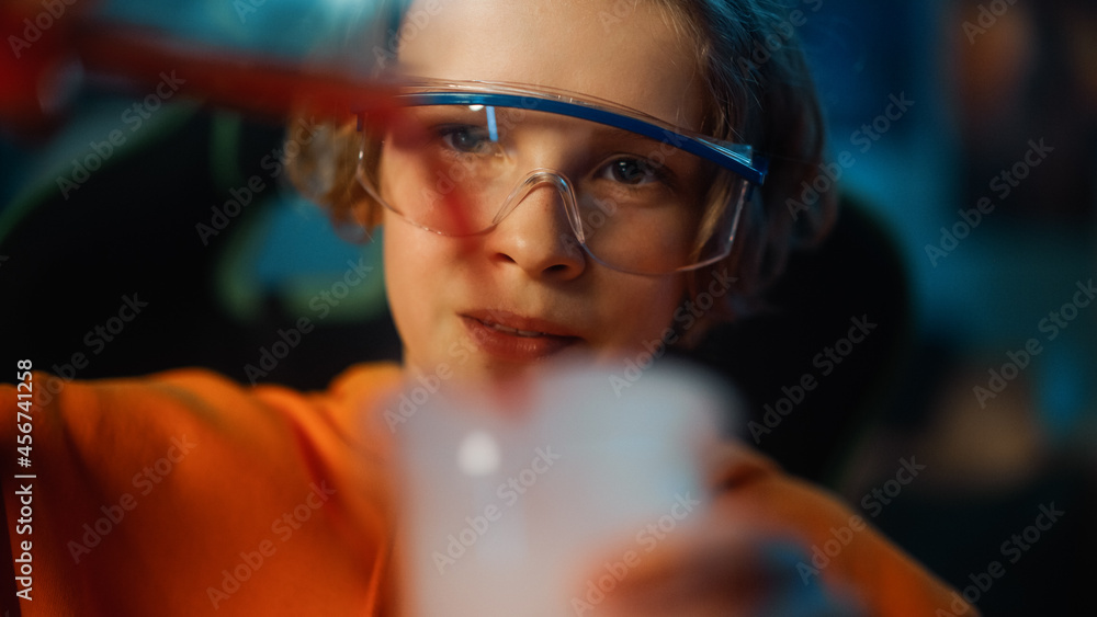 戴着安全护目镜的聪明男孩在家里混合烧杯中的化学物质。青少年进行教育