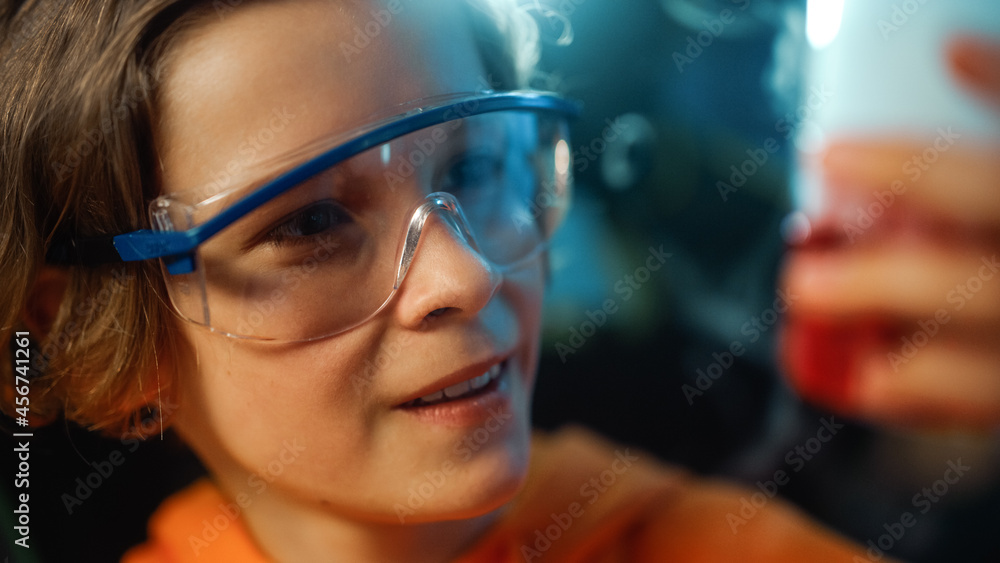 戴安全护目镜的聪明男孩在家里把烧杯里的化学物质混合在一起。青少年进行教育