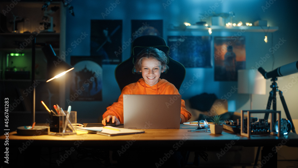 聪明的小男孩在家里黑暗舒适的房间里使用笔记本电脑。快乐的青少年浏览教育
