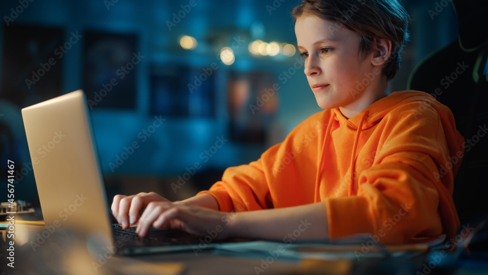 聪明的小男孩在家里黑暗舒适的房间里使用笔记本电脑。快乐的青少年浏览教育