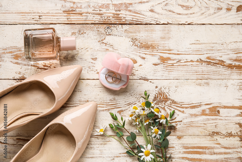 轻木背景上有结婚戒指、新娘鞋、香水瓶和一束鲜花的盒子