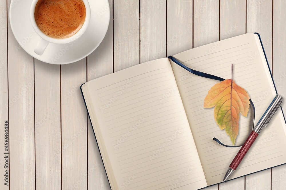 秋天，在乡村的木桌上放一本带时尚钢笔的空白日记，配一杯茶