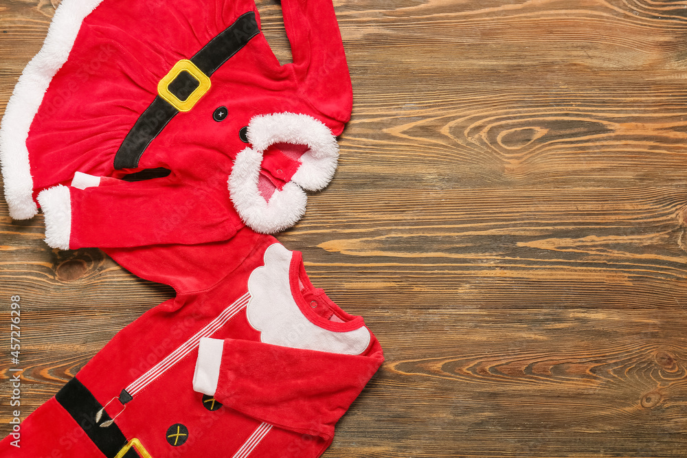 木制背景下为婴儿设计的时尚圣诞老人服装