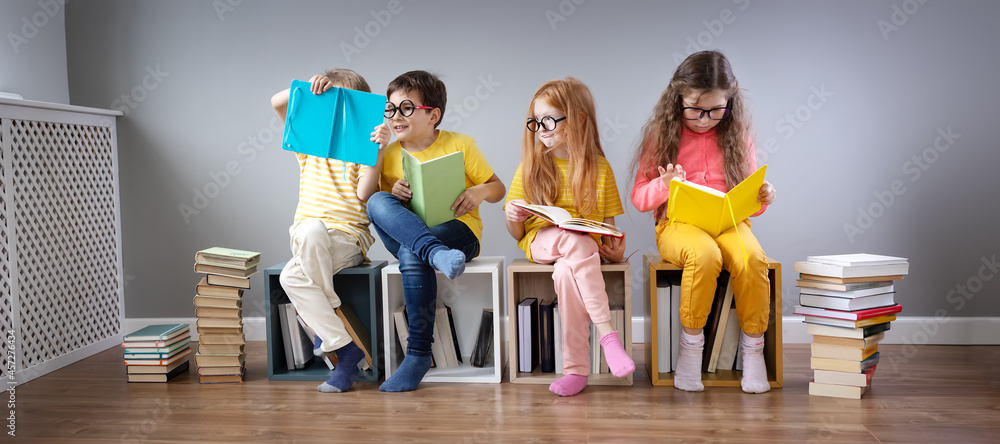 一群孩子坐在房间里的书堆和书架上阅读