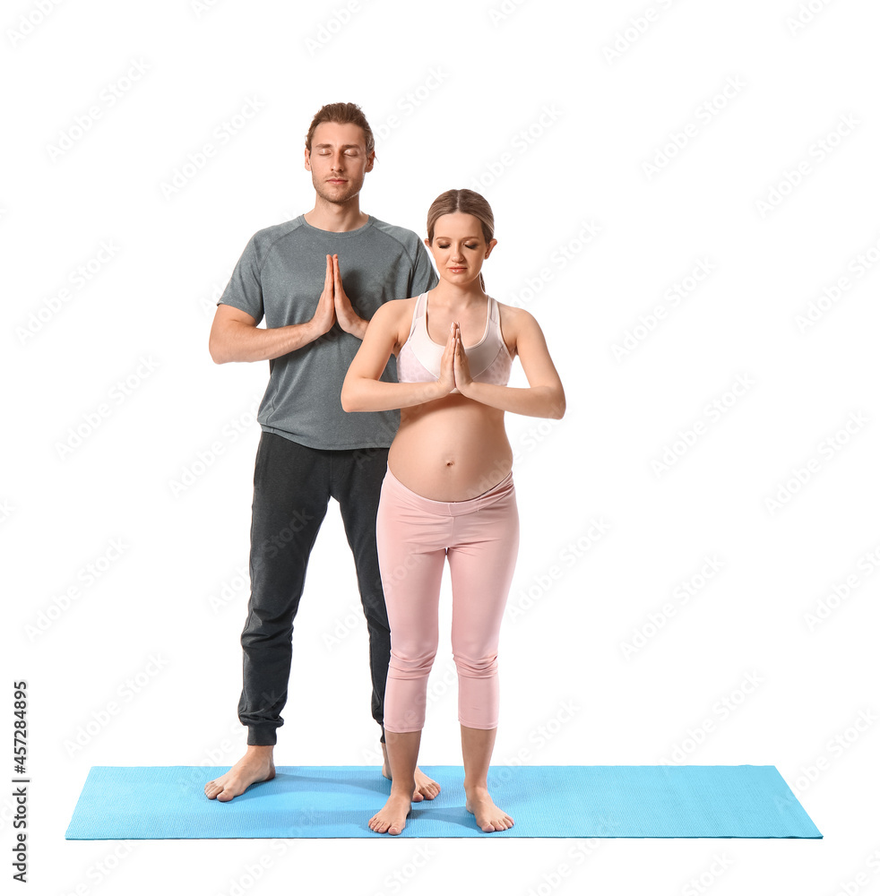 年轻的孕妇和她的丈夫在白色背景下练习瑜伽
