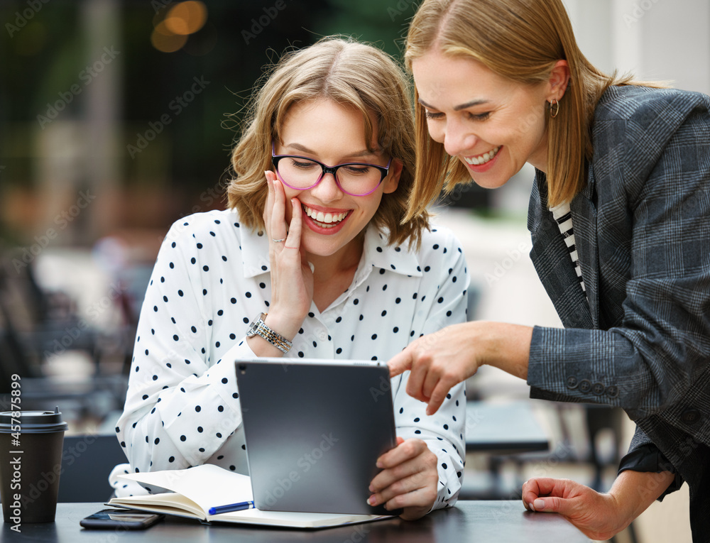 兴奋的成功商业女性在户外咖啡馆看着数字平板电脑，表情愉悦