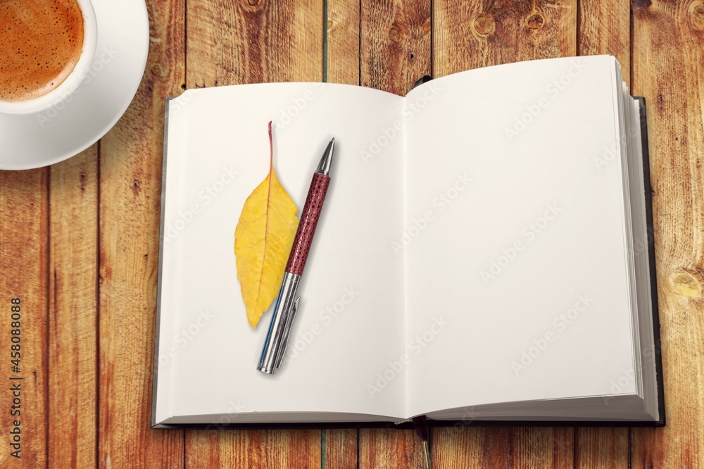 秋天，在乡村的木桌上放一本带时尚钢笔的空白日记，还有一杯茶