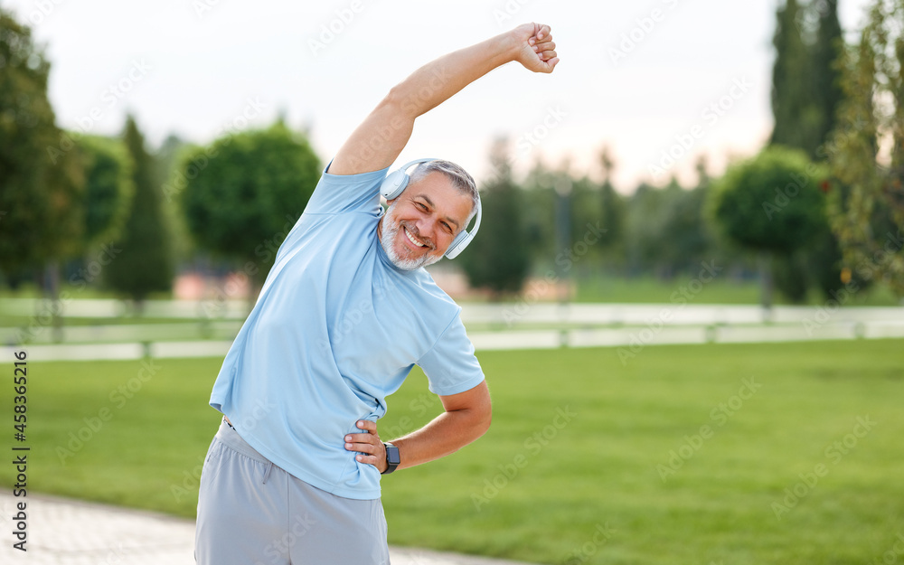 快乐的退休老人在户外锻炼时手臂举过头顶做侧边伸展运动