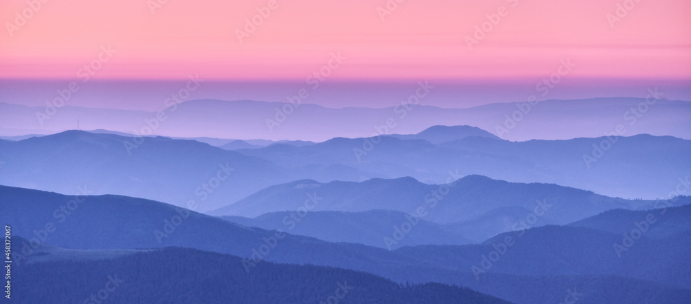 秋天日落时，雾中的山脊和粉红色的天空。雾蒙蒙的山脉，美丽的风景