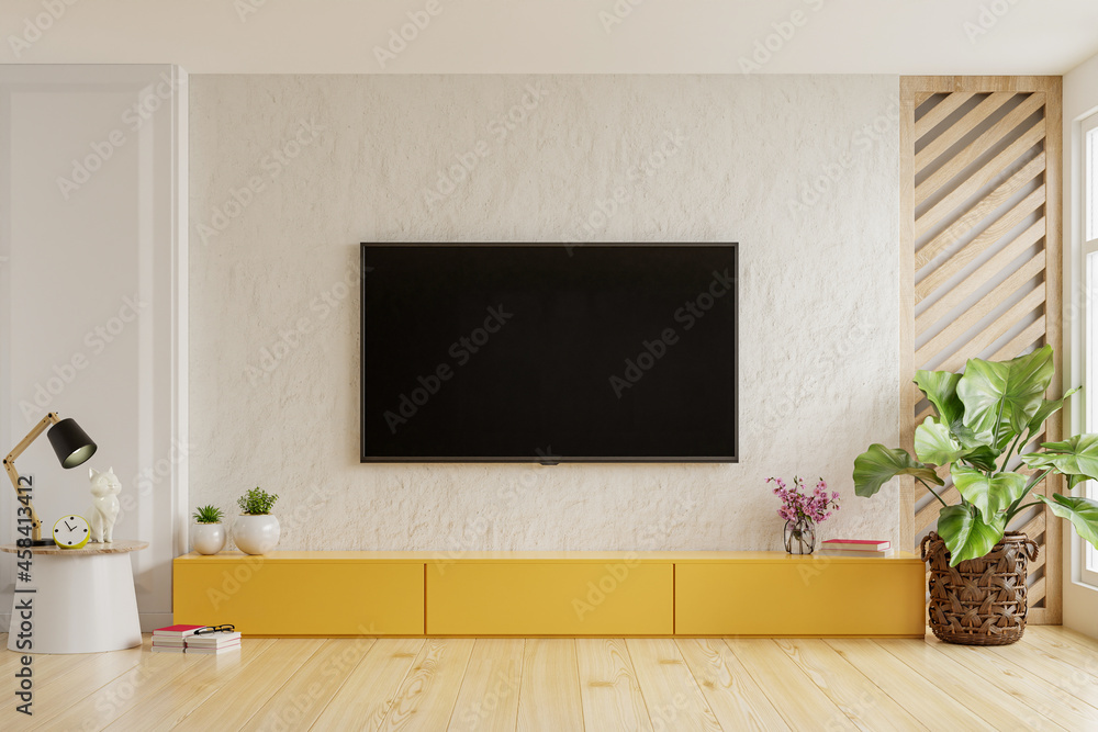 On a plaster wall background, a TV is mounted on a yellow cabinet in a modern living room