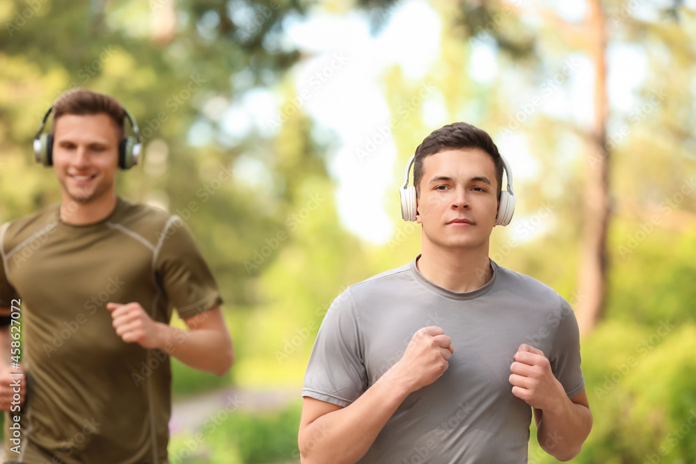 戴着耳机的运动型年轻男子在公园跑步