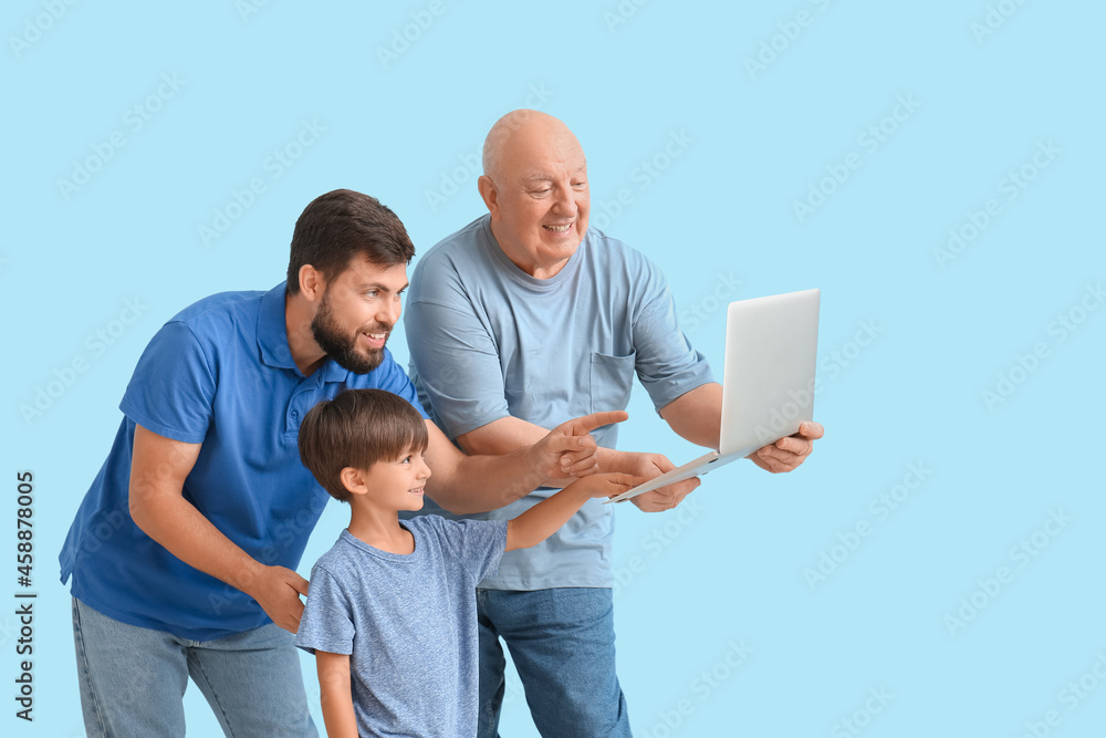 快乐的男人，他的小儿子和父亲，彩色背景的笔记本电脑