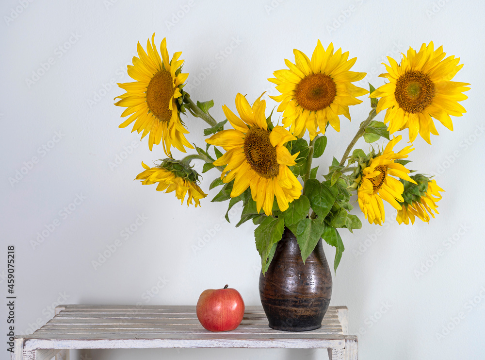Beautiful bouquet of sunflowers in vase and an apple. Autumn still life