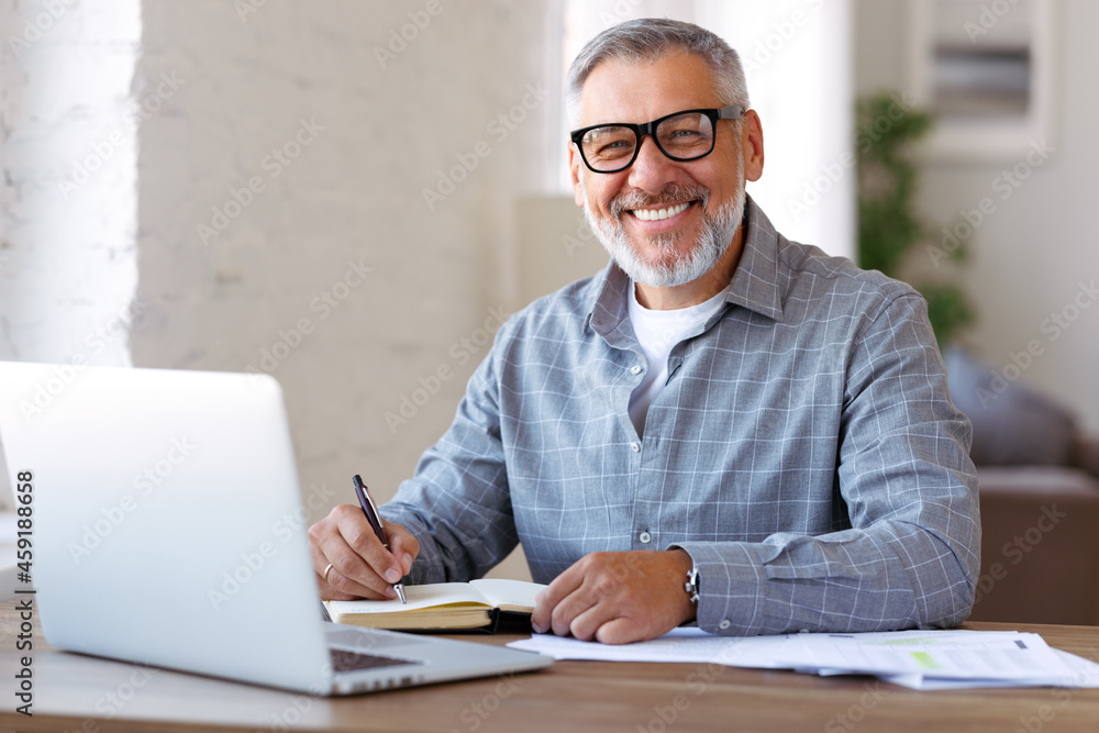 快乐的退休养老金领取者在家里用笔记本电脑在线学习