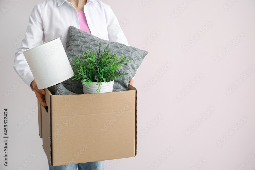 女人拿着衣柜盒子，背景是枕头、灯和室内植物