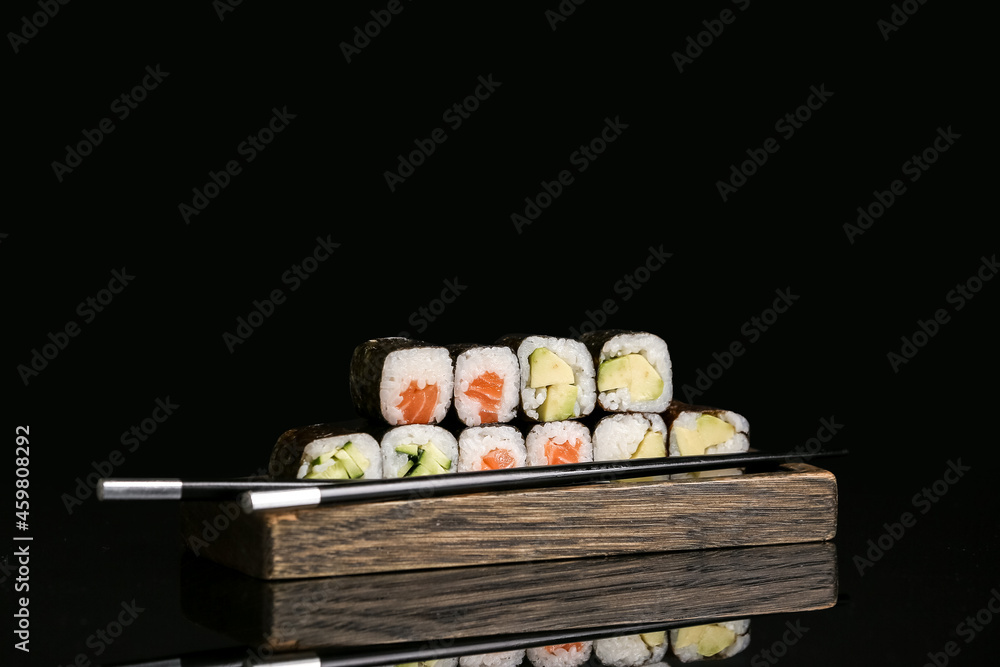 深色背景下有美味的maki卷和筷子的木托盘