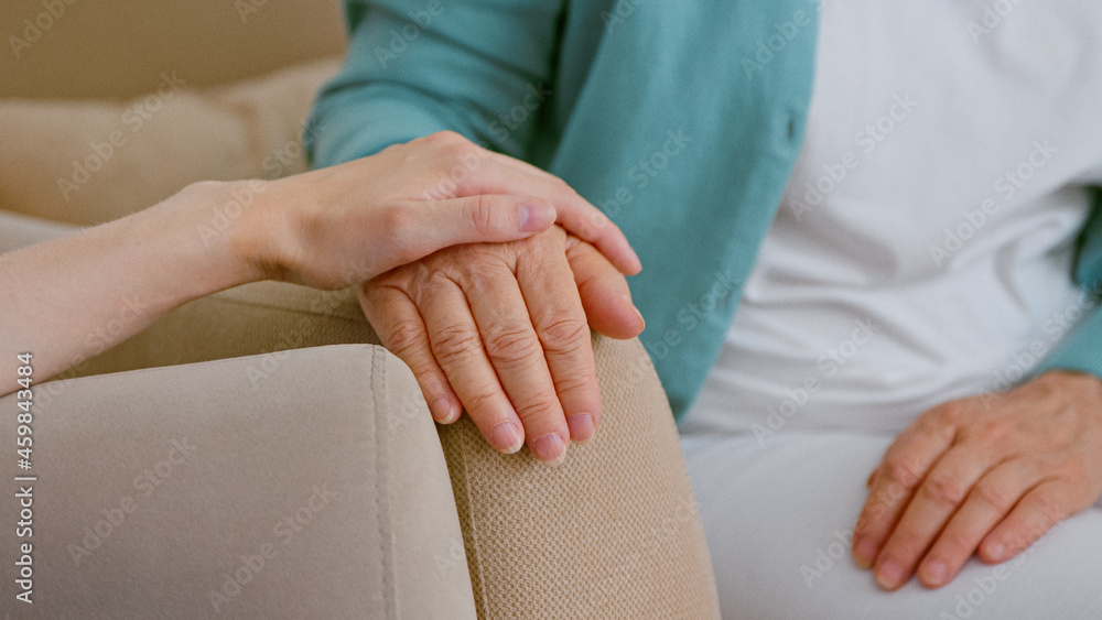 护理人员为坐在灯光室扶手椅上触摸手的老年女士患者欢呼