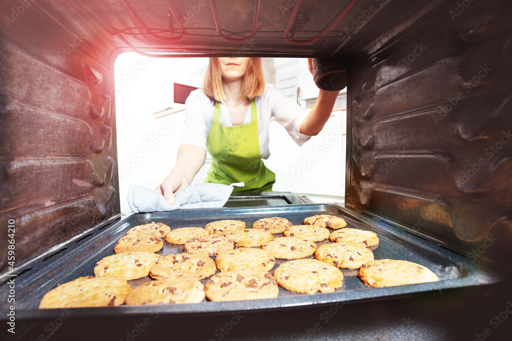 女人打开烤箱检查新鲜出炉的饼干