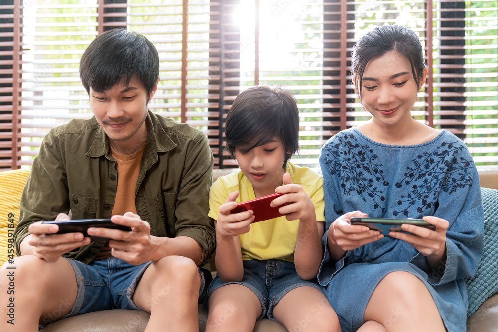 家庭品质的时光，亚洲父母和儿子坐着放松地玩游戏机或聪明地一起开怀大笑