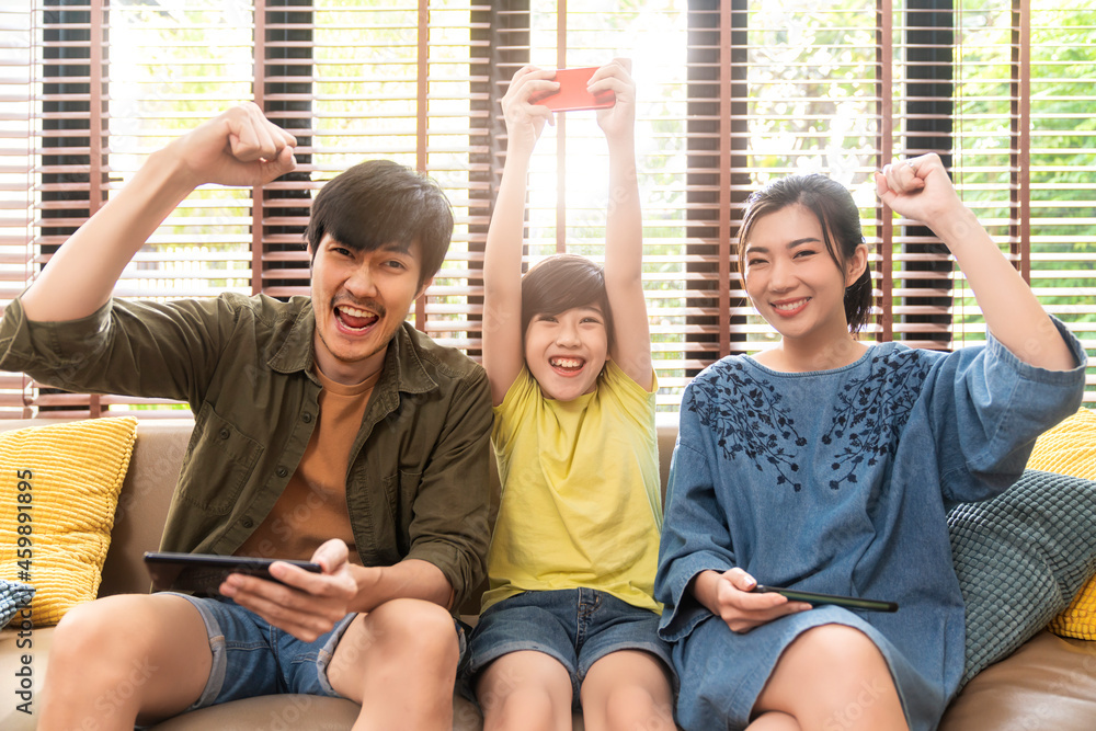 家庭品质的时光，亚洲父母和儿子坐着放松地玩游戏机或聪明地一起开怀大笑