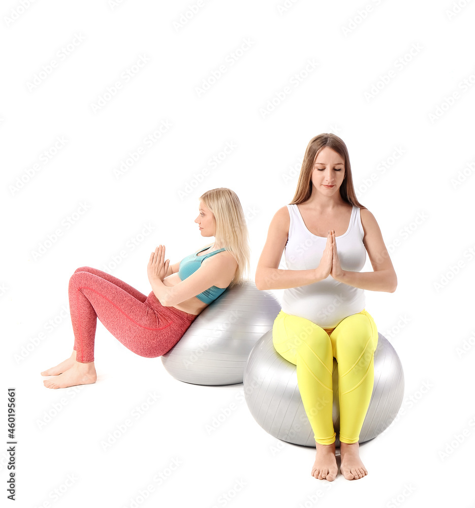 有健身球的年轻孕妇在白色背景下练习瑜伽