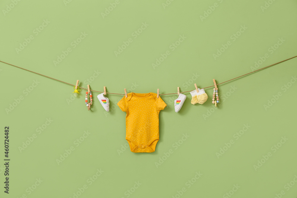 时尚的婴儿服装、鞋子和配饰挂在绳上，以彩色为背景