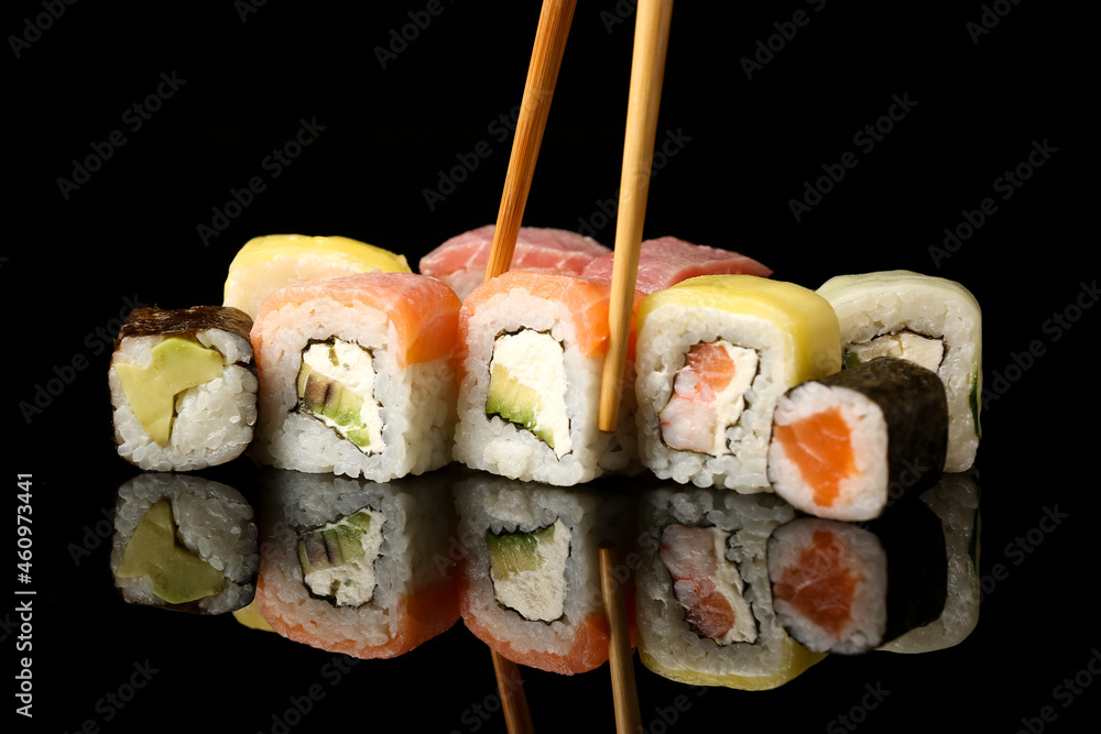 木筷子在深色背景下取美味的寿司卷