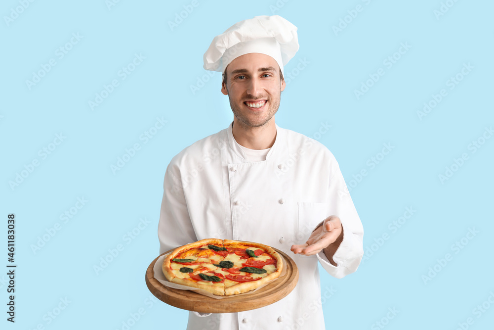 英俊的厨师在蓝色背景下展示美味的披萨