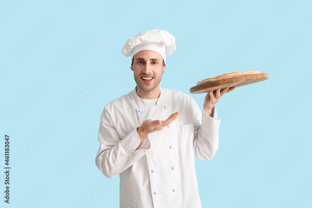 英俊的厨师在蓝色背景上展示美味的披萨