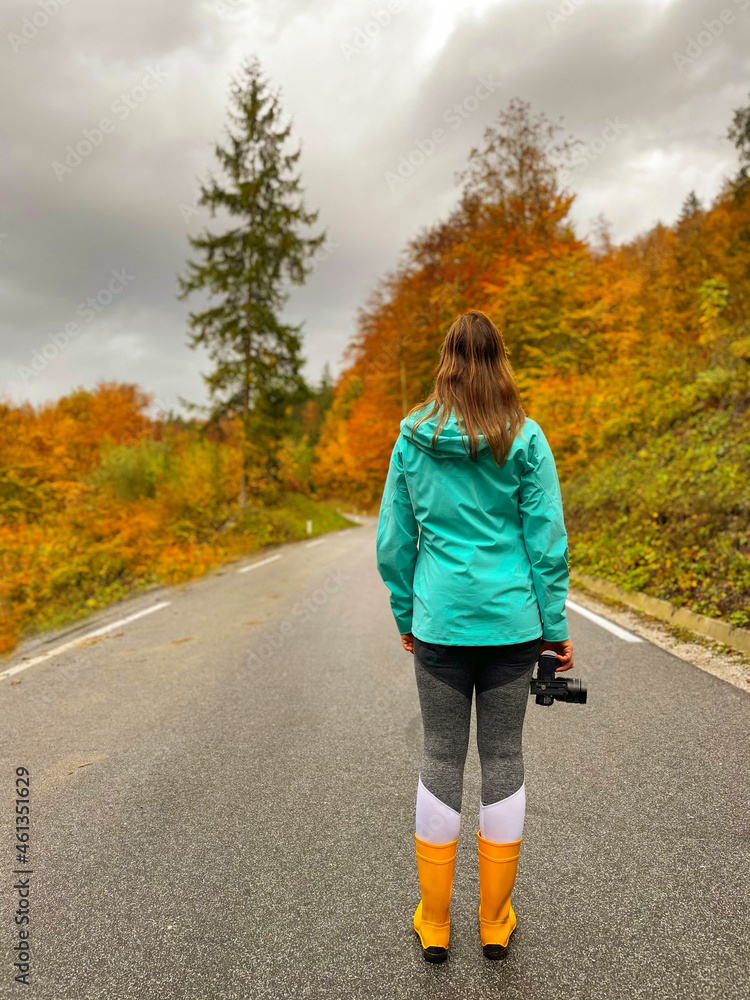 垂直：女性摄影师在秋季公路旅行中找到灵感。