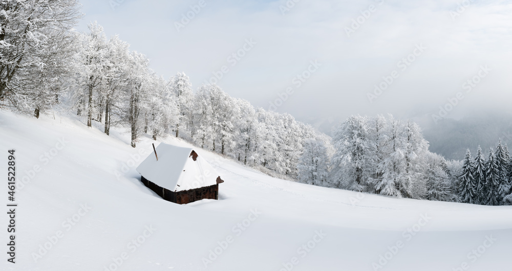 Fantastic winter panoramical landscape with wooden cabin in snowy forest. Cozy house in Carpathian m