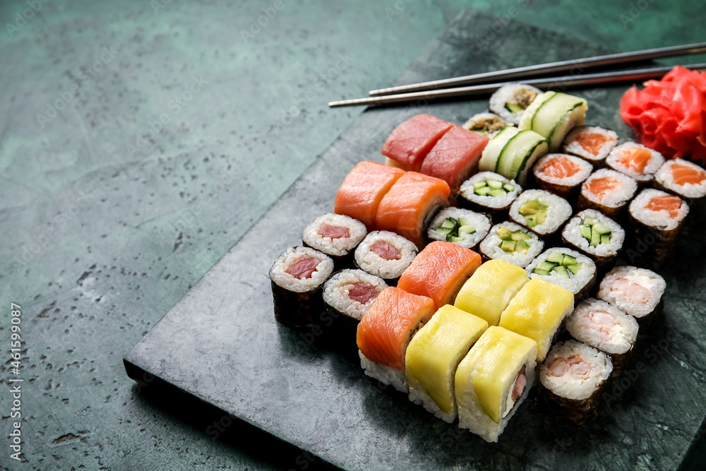 Board with set of delicious sushi rolls on color background