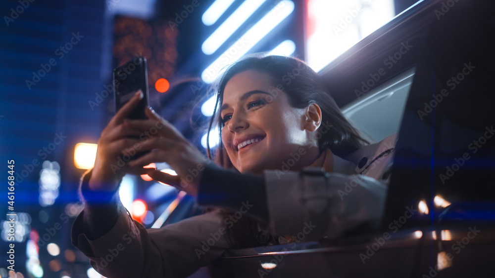 Excited Female is Looking Out of the Window from Backseat of a Car at Night. Woman Taking Photos and