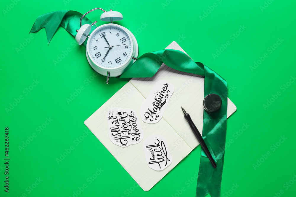 绿色背景带文字、笔尖、闹钟和缎带的笔记本
