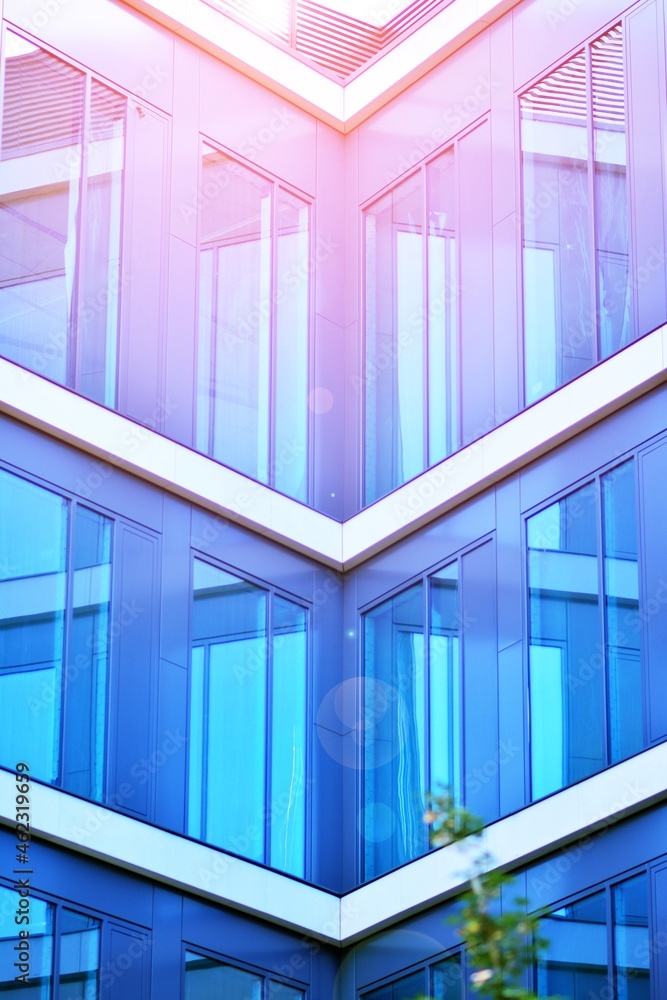 在晴朗的天空背景下，玻璃立面的现代办公楼。办公室的透明玻璃墙