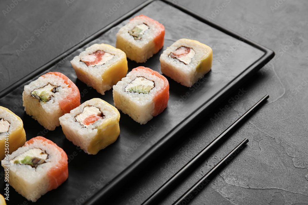 深色背景下的美味寿司卷和筷子，特写