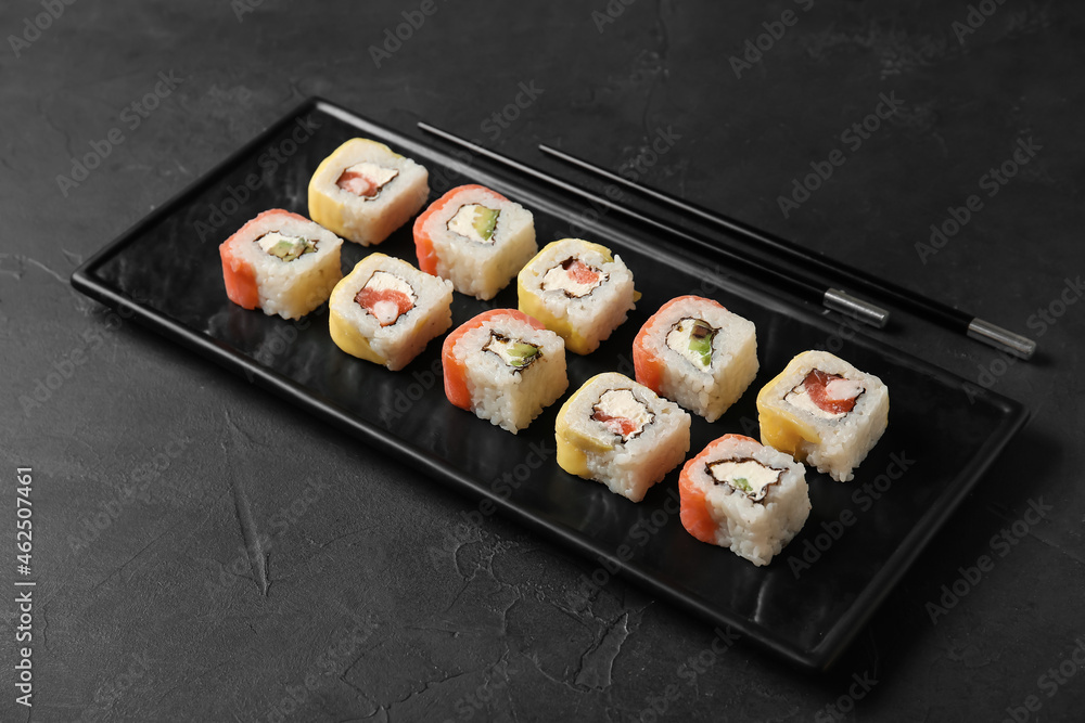 深色背景上有一套美味的寿司卷和筷子的木板