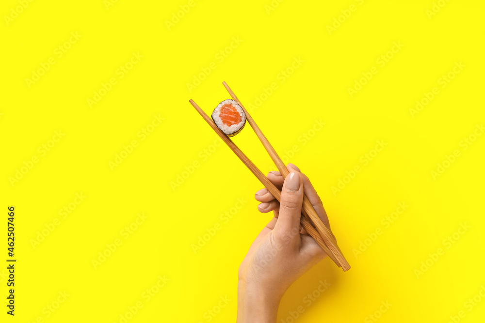 女人拿着筷子，彩色背景上有美味的寿司卷