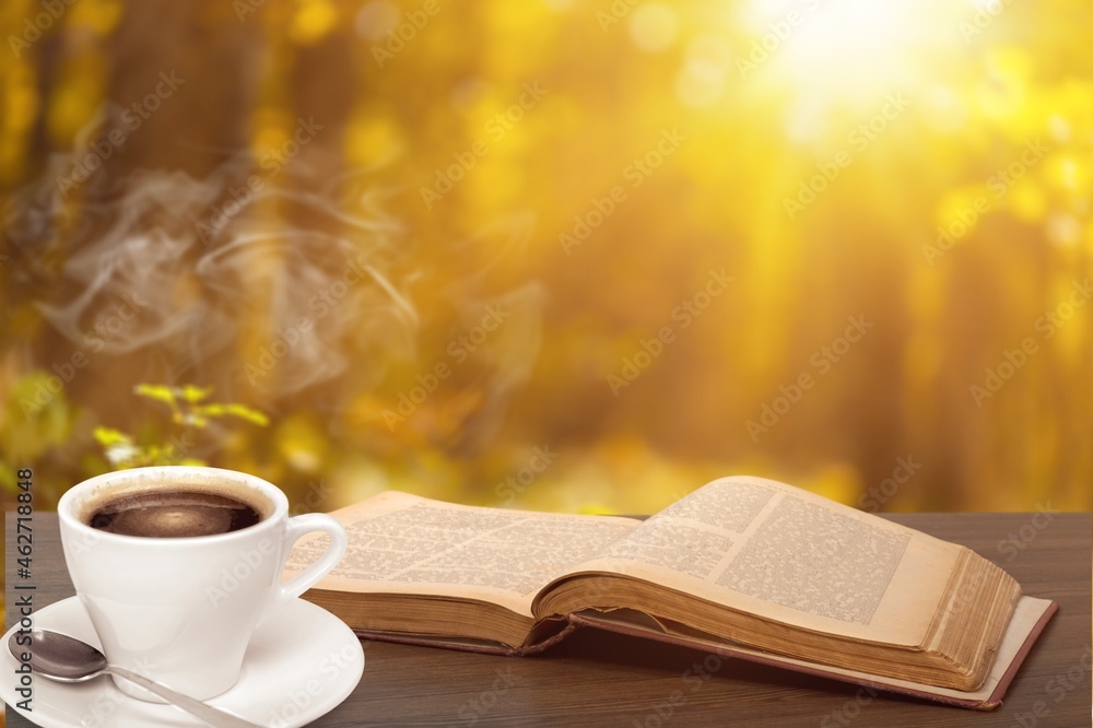 Open Book And Steaming Cup On Wooden Table With Autumn Sunrise Background