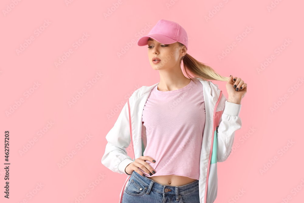 戴棒球帽的女人在粉色背景下抚摸头发