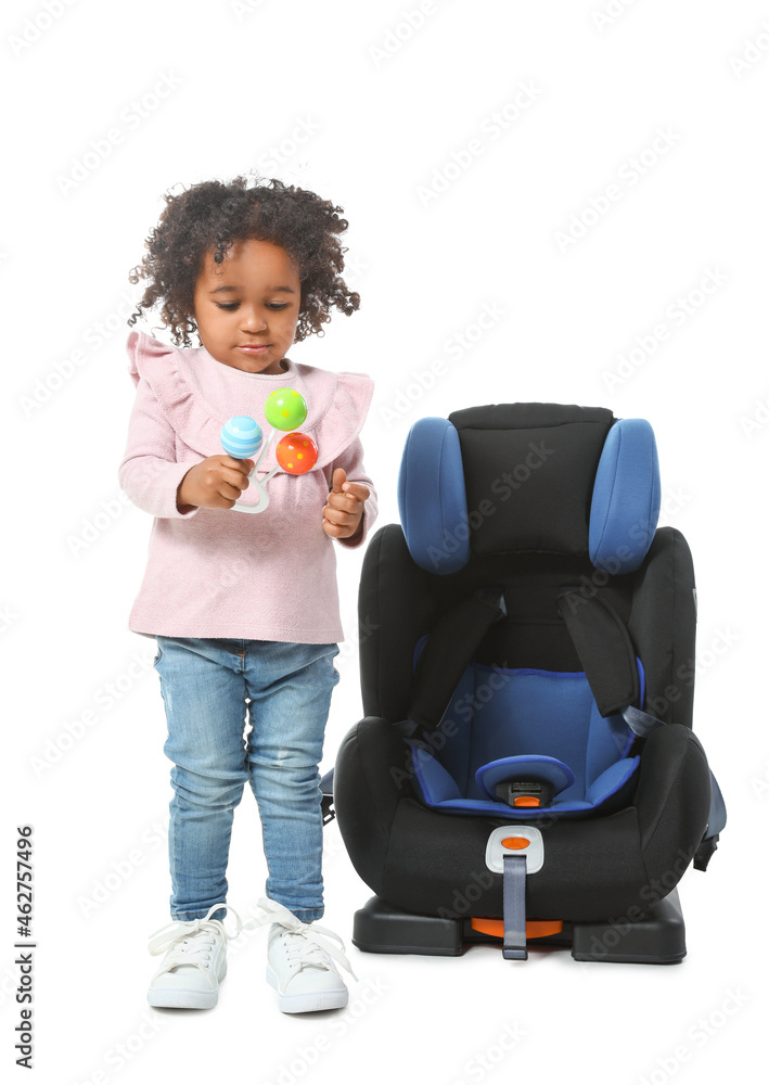 白色背景下，在汽车安全座椅附近拿着玩具的非洲裔小女孩