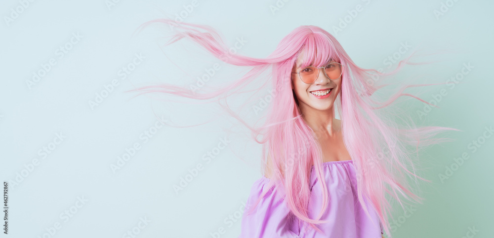 粉色头发的年轻亚洲女性在绿色背景下摆造型