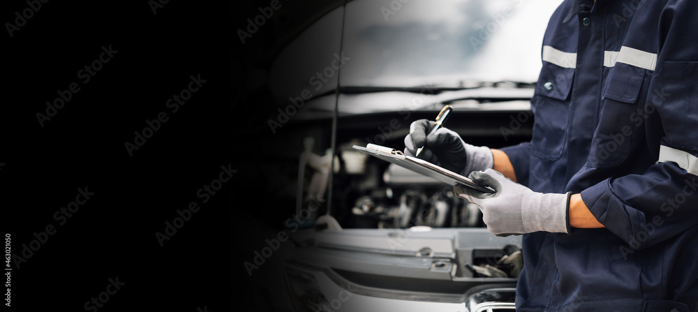 Car service, repair, maintenance concept,auto mechanic man or Smith writing to the clipboard at work