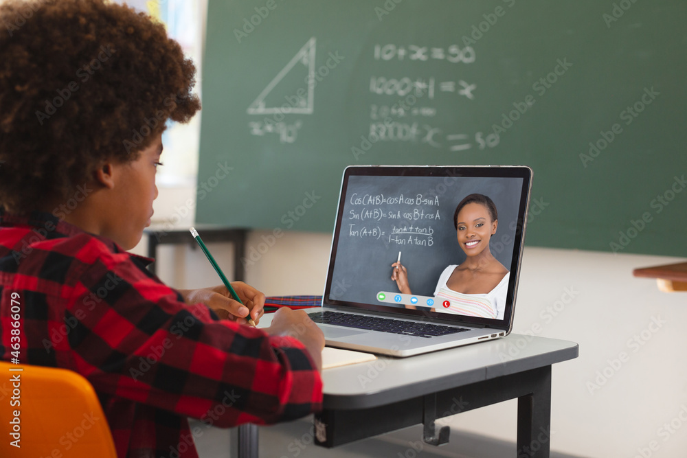 非裔美国男孩用笔记本电脑进行视频通话，屏幕上有非裔美国女教师