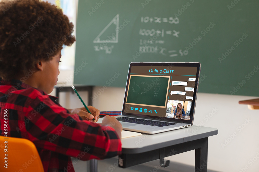 非裔美国男孩用笔记本电脑进行视频通话，屏幕上有微笑的白人女老师