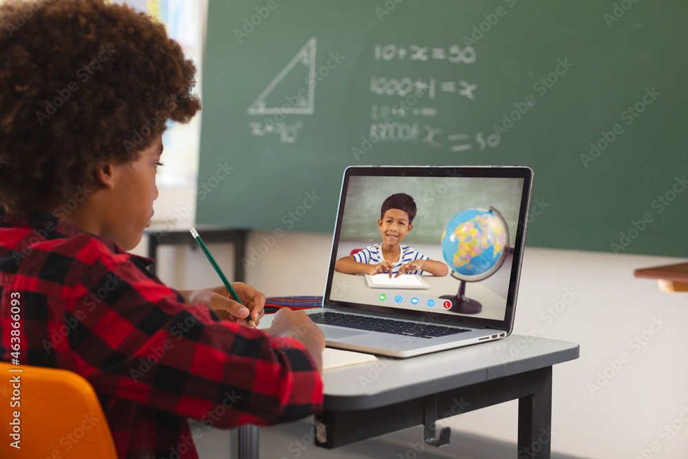 非裔美国男孩用笔记本电脑进行视频通话，屏幕上有混血小学生