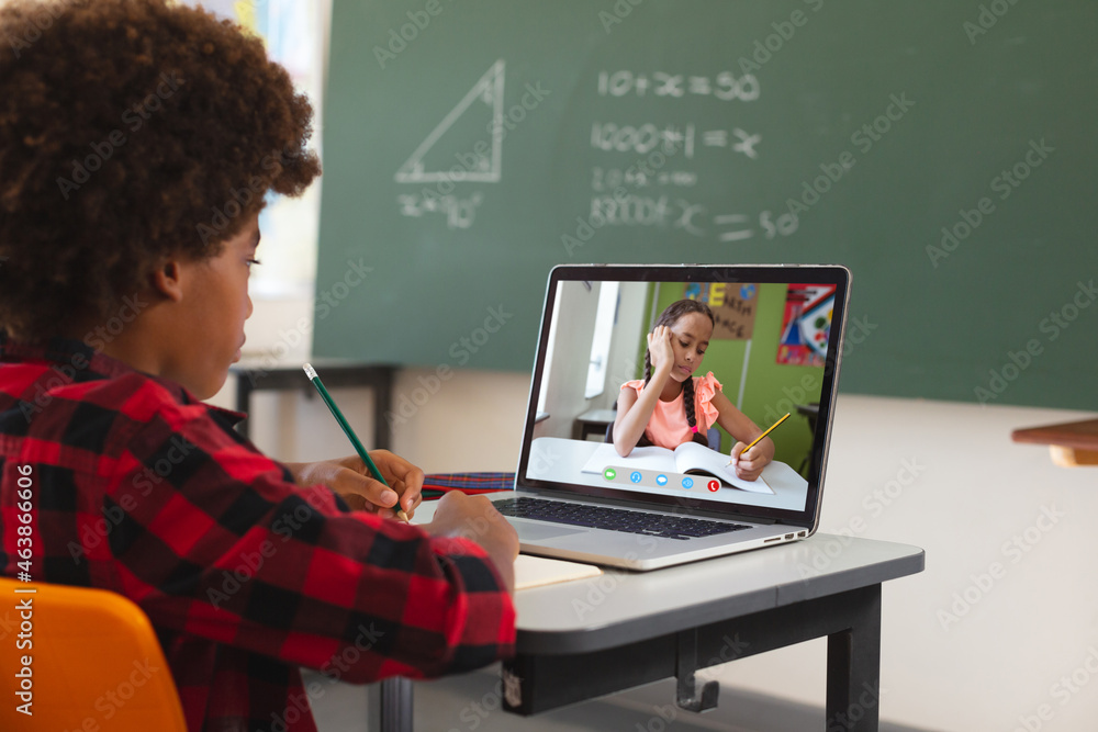 非裔美国男孩用笔记本电脑进行视频通话，屏幕上有混血小学生