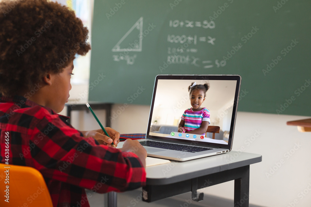 非裔美国男孩用笔记本电脑进行视频通话，屏幕上有小学生